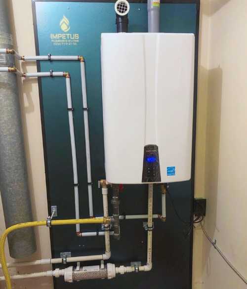 Navien Tankless Water Heater with the Impetus Plumbing & Heating logo behind it.